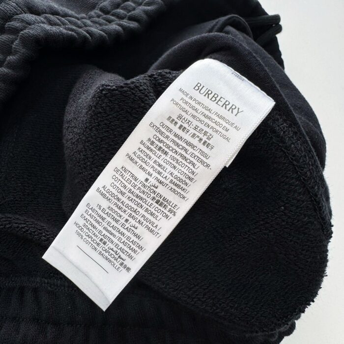 Etichetta Burberry su maglione nero morbido, dettagli di cura e eleganza di lusso.