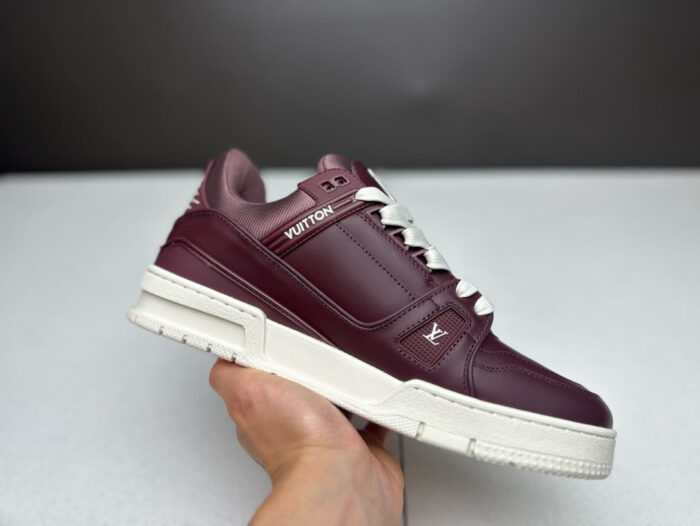 Sneaker di lusso in pelle burgundy con suola bianca, dettagli eleganti e logo Vuitton.
