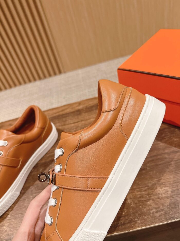 Sneakers in pelle caramello di alta qualità con suola bianca e dettagli metallici eleganti.