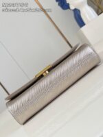 Borsa clutch elegante in metallo champagne con chiusura dorata e design raffinato.