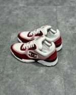 Sneakers Chanel di lusso bianco, rosso e nero con logo iconico e stile sporty-chic.