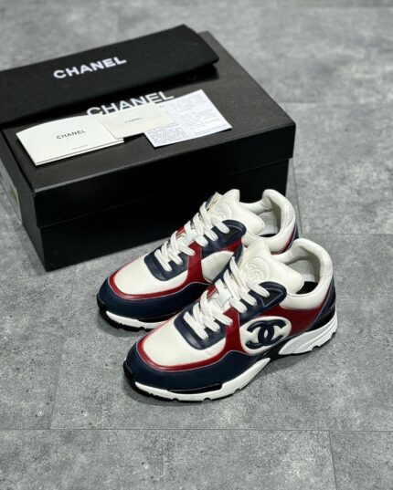 Sneakers Chanel di lusso con logo iconico, design sporty e scatola elegante nera.