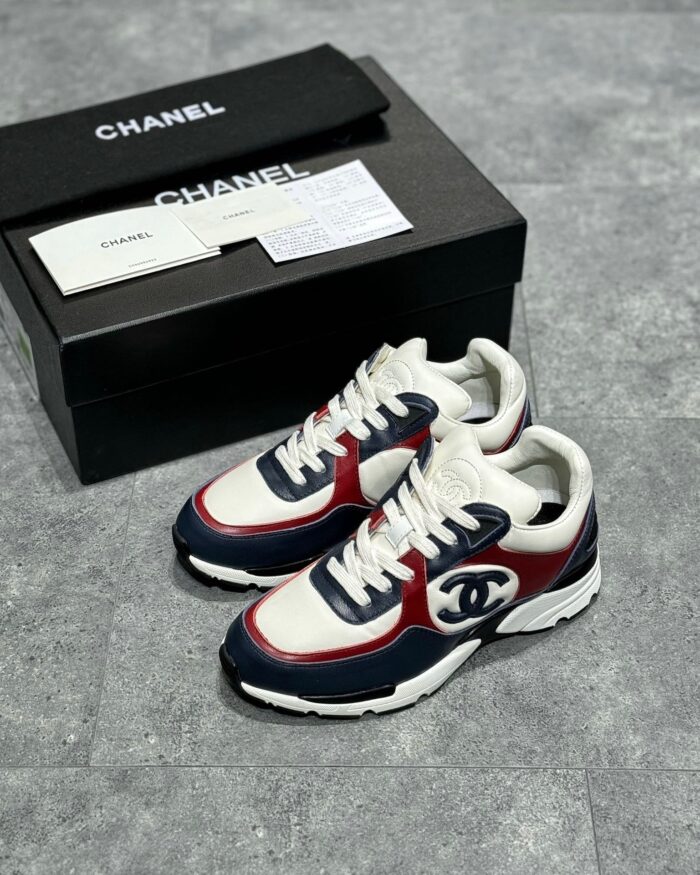 Sneakers Chanel di lusso con logo iconico, design sporty e scatola elegante nera.