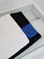 Camicia bianca e nera con patch blu, esposizione elegante in vetrina di moda di lusso.