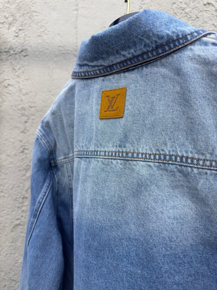 Giacca in denim blu con logo dorato e stile di lusso, perfetta per un look elegante e casual.