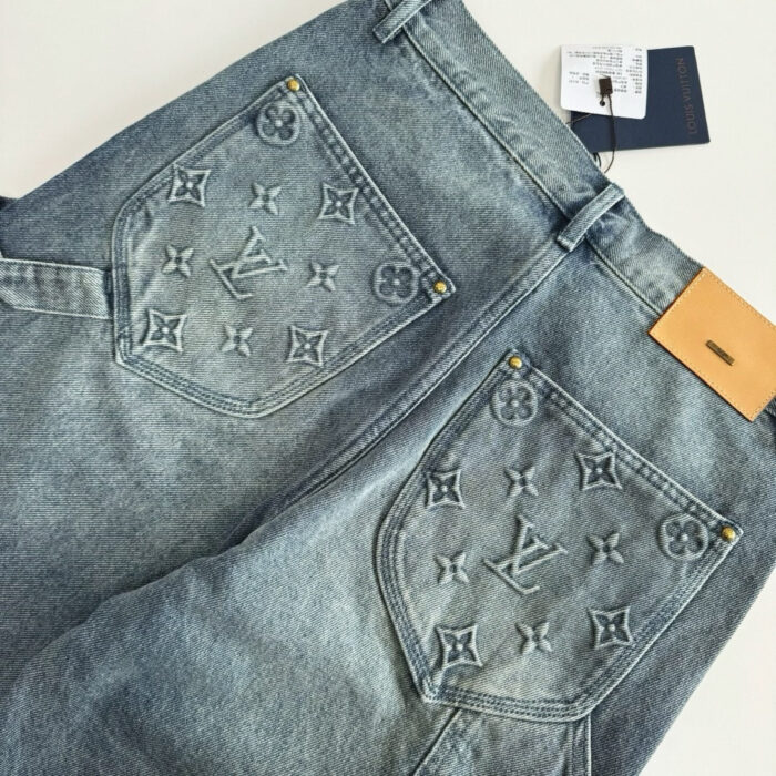 Jeans di lusso in denim chiaro con ricami logo, rivetti oro e patch in pelle.