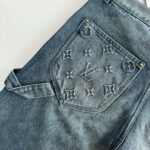 Jeans Louis Vuitton con ricami, dettagli dorati e jeans sfumato, stile casual e di lusso.