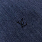 Dettaglio di denim blu con logo minimalista in fibra nera, eleganza moderna e raffinata.