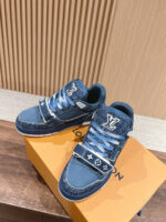 Sneaker da uomo in denim blu, dettagli bianchi e suola pulita su scatola arancione di lusso.