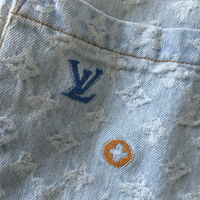 Jeans in denim chiaro con ricami Louis Vuitton e dettagli iconici del brand.