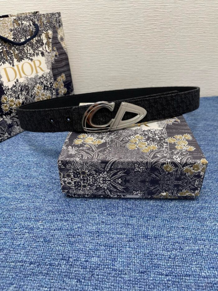 Cintura Dior nera con fibbia CD, packaging elegante e sfondo blu raffinato.