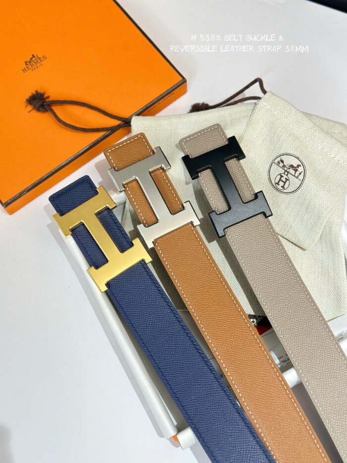 Set di cinture di lusso in pelle con fibbie geometriche e packaging elegante.
