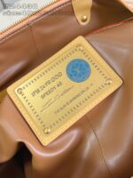 Interno di borsa di lusso con targhetta dorata e dettagli eleganti in pelle marrone.