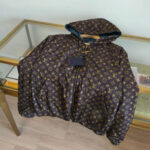 Giacca puffer di lusso con logo dorato, cappuccio colorato e design elegante.