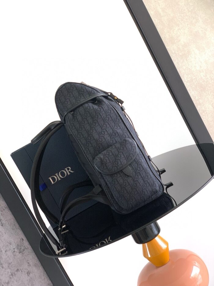 Borsa Dior elegante su superficie riflettente con scatola blu e dettaglio arancione.