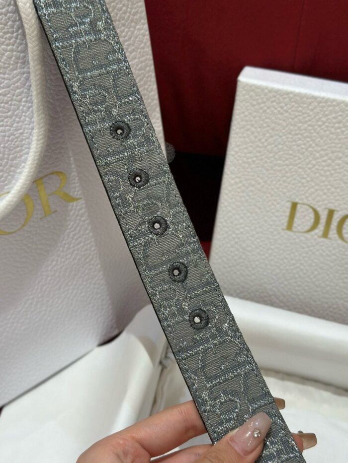 Cintura Dior di lusso con bottoni neri e packaging elegante in crema e oro.