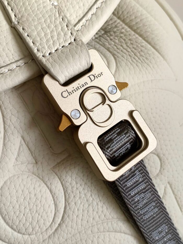 Fermo Dior in metallo dorato su borsa in pelle colorata, dettaglio di lusso e stile.