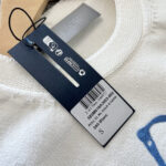 Etichetta di moda su tessuto bianco con logo navy e dettagli di cura.