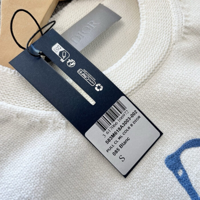 Etichetta di moda su tessuto bianco con logo navy e dettagli di cura.