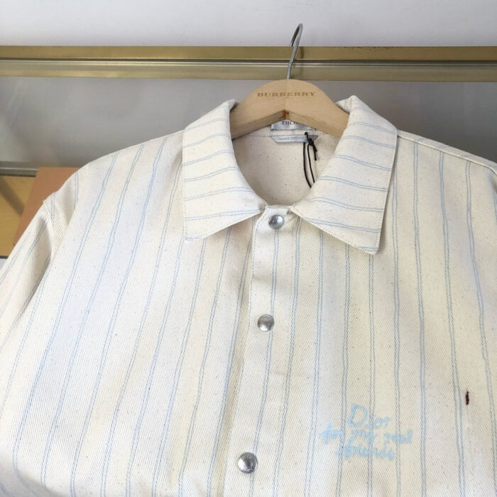 Camicia Dior righe crema, logo blu, stile elegante e tessuto di alta qualità.