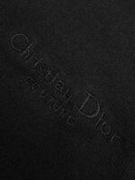 Logo Dior in rilievo su tessuto nero di lusso, simbolo di eleganza e artigianato raffinato.