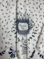 Tessuto Dior con motivi floreali delicati e dettagli eleganti, perfetto per capi di alta moda.