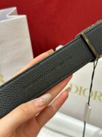Cintura Dior in pelle grana, design elegante, con fermaglio minimalista, simbolo di lusso e stile.