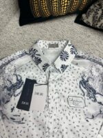 Camicia Dior bianca elegante con motivo floreale blu, dettaglio di lusso e stile sofisticato.