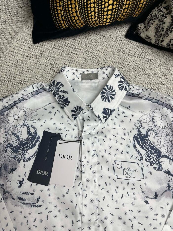 Camicia Dior bianca elegante con motivo floreale blu, dettaglio di lusso e stile sofisticato.