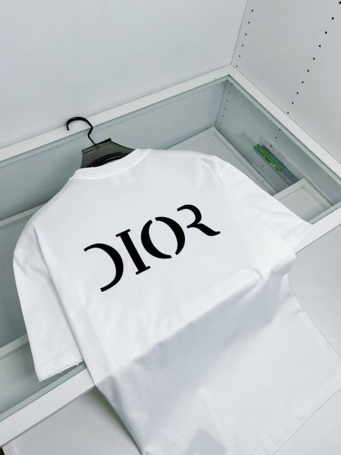 Maglietta Dior bianca in vetrina di lusso con logo nero e design elegante.