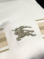 Tessuto elegante con logo a cavallo ricamato e Strisce moderne in tonalità beige.