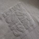 Logo Loewe ricamato su tessuto di alta qualità, simbolo di lusso e artigianato raffinato.