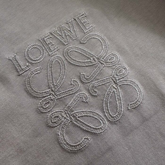 Logo Loewe ricamato su tessuto di alta qualità, simbolo di lusso e artigianato raffinato.