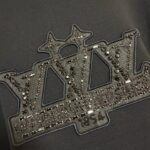 Logo moderno con ricami, strass e dettagli storici di VIVI 1854 in grigio e argento.