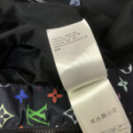 Etichetta di lusso con motivi floreali colorati su vestito elegante nero.