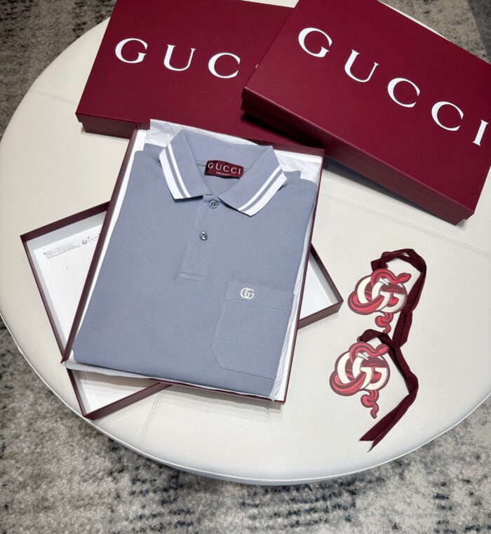 Set regalo Gucci: polo grigia, scatole di lusso e accessori eleganti in mostra sofisticata.