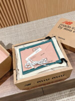 Scatola Miu Miu con moda verde e rosa, elegante packaging di lusso e dettagli raffinati.