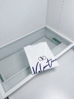 Maglietta bianca di lusso in vetrina con logo e nome Valentin in display elegante.