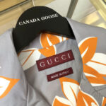 Camicia floreale con etichette Gucci e Canada Goose, stile estivo e lusso.