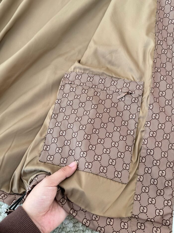 Dettaglio di cappotto di lusso con tasca monogramma Gucci, tessuti eleganti e artigianato raffinato.