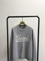 Maglione Gucci grigio con logo in stile cursivo, elegante e di lusso per uomo.