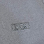 Dettaglio di tessuto grigio con logo Dior ricamato, stile minimalista ed elegante.