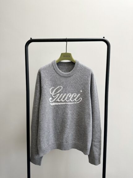 Maglione grigio Gucci con ricamo del logo, stile casual e di lusso, display minimalista.