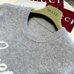 Maglione Gucci grigio di lusso su gancio elegante con etichette rosse e dettagli raffinati