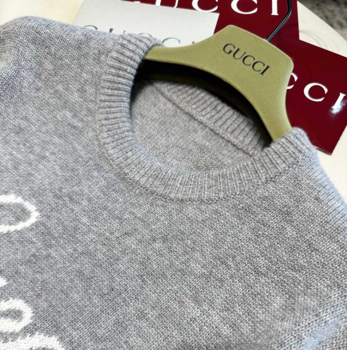 Maglione Gucci grigio di lusso su gancio elegante con etichette rosse e dettagli raffinati