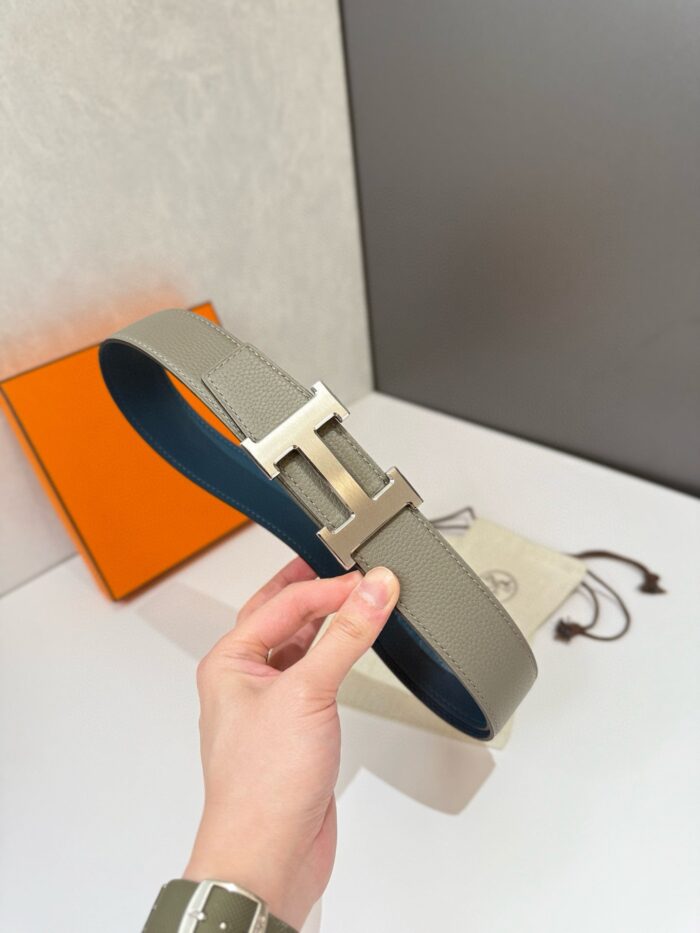 Cintura di lusso in pelle grigia con fibbia doppia-H, elegante e di alta qualità.