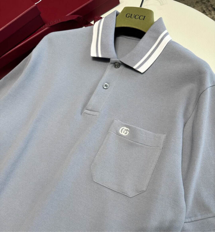 Polo Gucci azzurro con colletto a strisce e logo ricamato, stile moderno e raffinato.