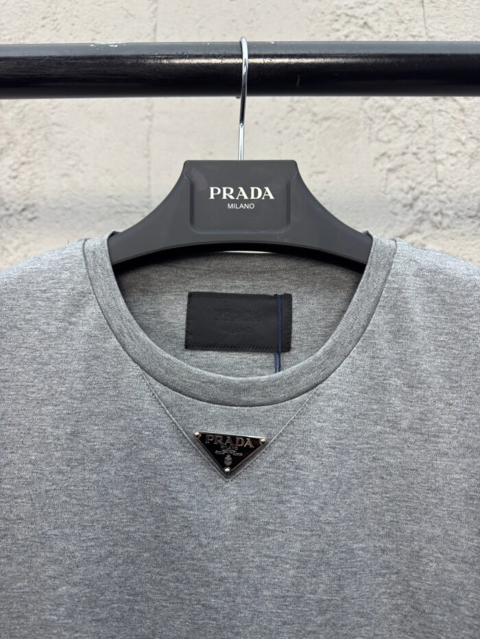 T-shirt grigia Prada con logo triangolare e dettagli di alta moda elegante e casual.