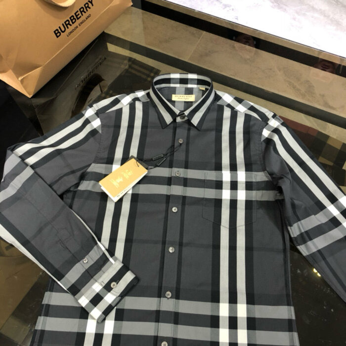 Camicia eleganza a quadri grigia, firma di lusso, su superficie riflettente e raffinata.