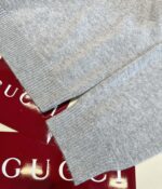 Maglione Gucci grigio di lusso con dettagli raffinati e etichette eleganti rosse.